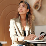 woman wearing blazer and blue denim jeans sitting on chair
